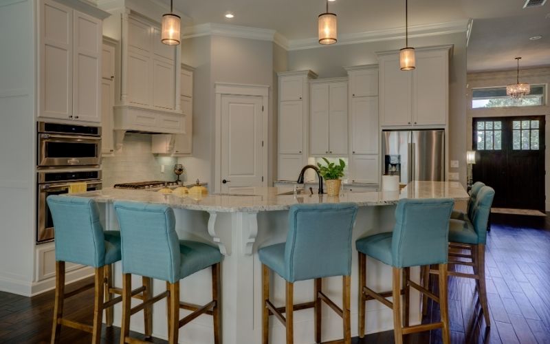 Dark wood floor with white kitchen and light colored furniture